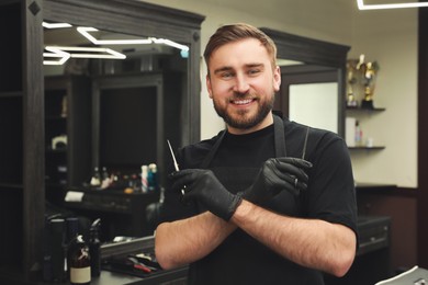 Photo of Happy hairdresser with professional tools in barbershop