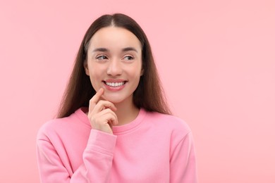 Photo of Beautiful woman with clean teeth smiling on pink background, space for text