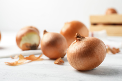 Ripe yellow onion bulbs on white wooden table, closeup