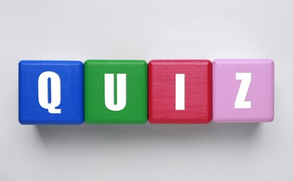 Photo of Colorful cubes with word Quiz on white background, top view