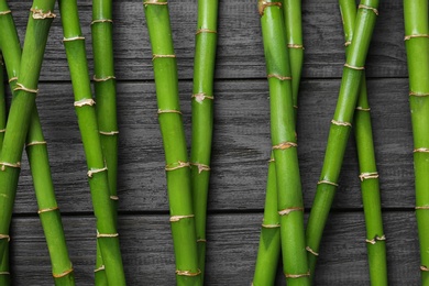 Photo of Green bamboo stems on black wooden background, top view