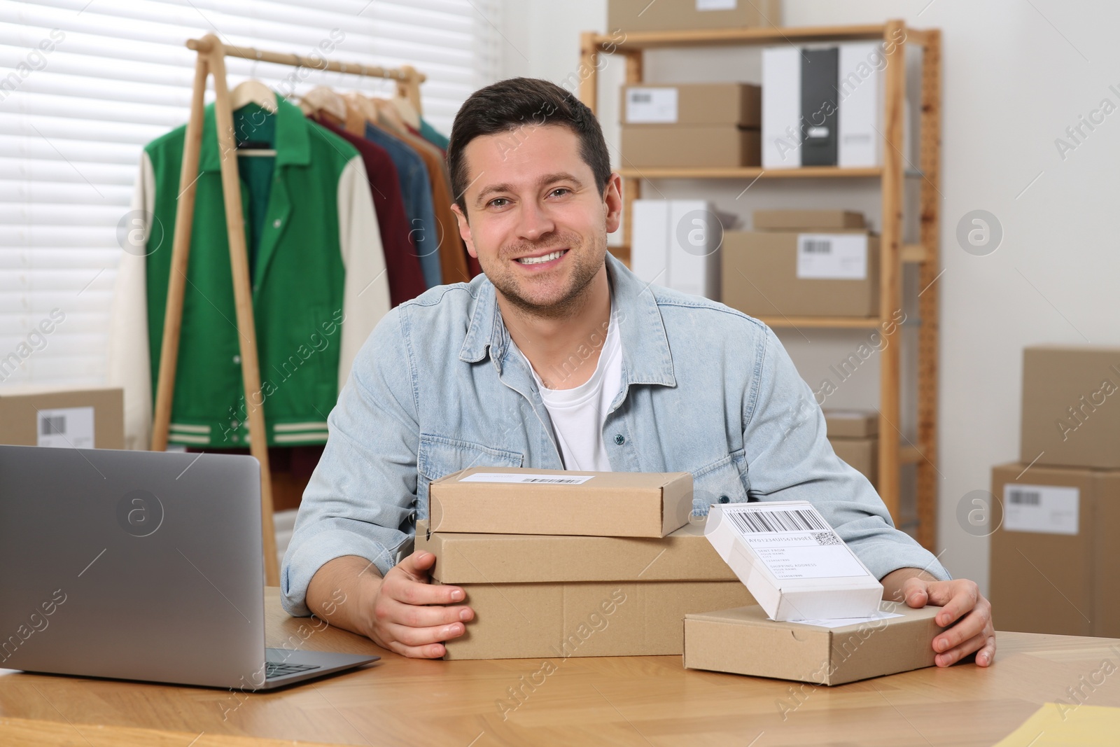 Photo of Seller with parcels and laptop in office. Online store