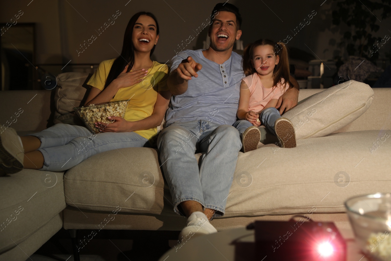 Photo of Family watching movie with popcorn on sofa at night