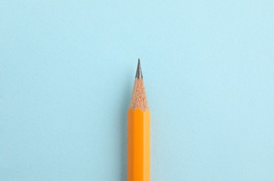 Photo of One sharp graphite pencil on light blue background, top view