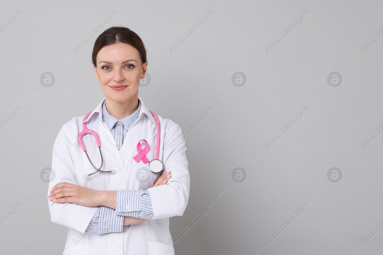 Photo of Mammologist with pink ribbon on grey background, space for text. Breast cancer awareness