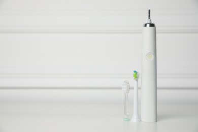 Electric toothbrush and replacement brush heads on white background, space for text