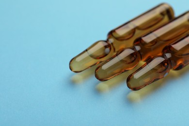 Medical ampoules with solution on light blue background, closeup. Space for text