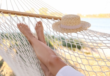 Photo of Young woman relaxing in hammock on beach, closeup. Summer vacation