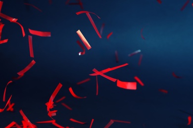 Photo of Shiny red confetti falling down on dark blue background