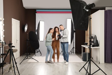 Professional photographer and makeup artist with model in studio