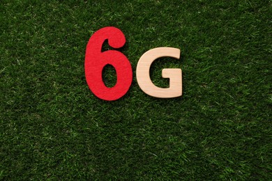 Photo of 6G technology, Internet concept. Number and letter on green grass, flat lay