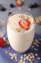 Photo of Tasty yogurt in glass, oats and berries on grey table