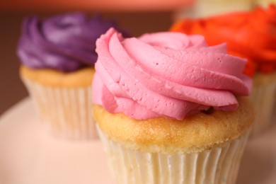 Delicious cupcakes with bright cream on plate, closeup