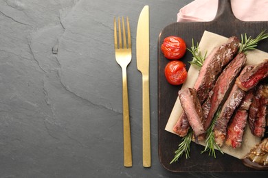 Delicious grilled beef with vegetables and rosemary served on dark gray table, top view. Space for text