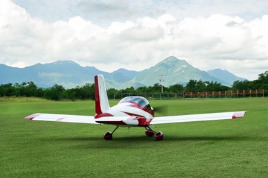 Photo of Modern airplane on green grass against mountains background