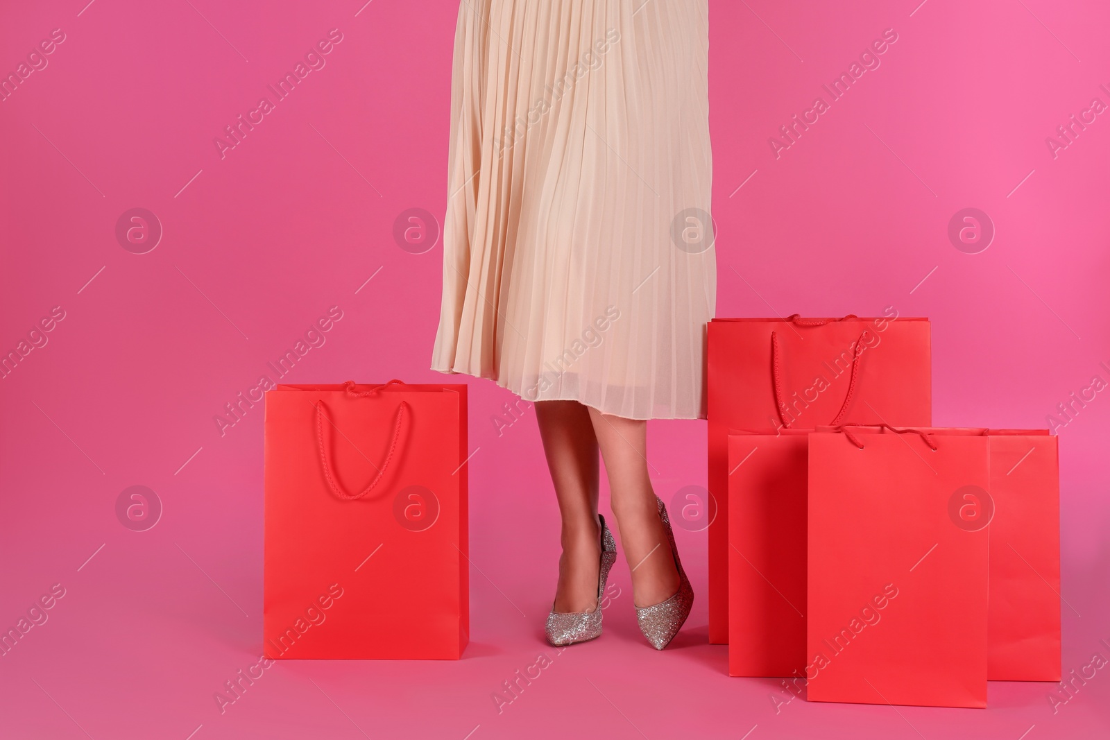 Photo of Woman with shopping bags on pink background, closeup. Black Friday Sale