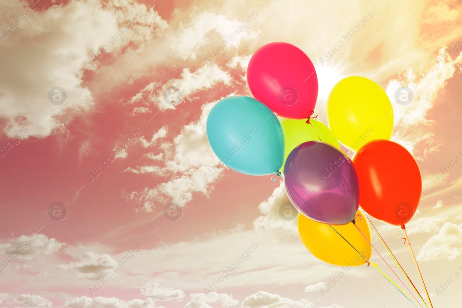 Image of Colorful balloons flying in bright sky with clouds. Space for text