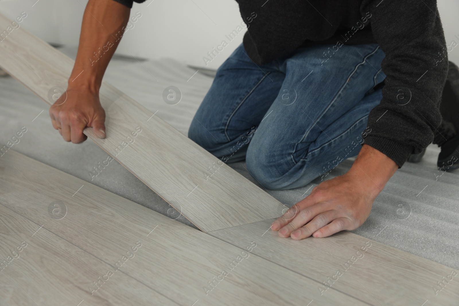 Photo of Worker installing new laminate flooring in room, closeup