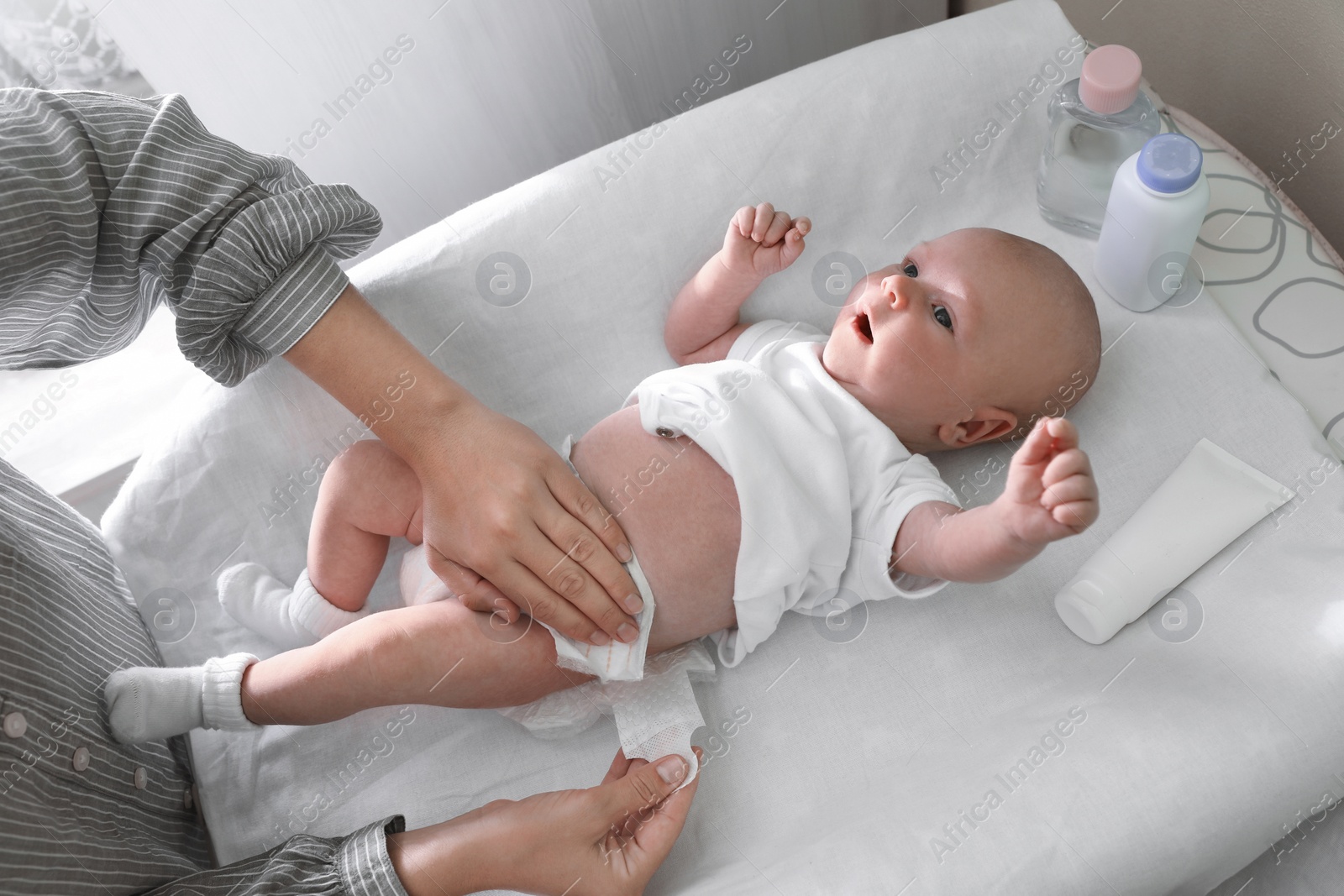 Photo of Mother changing her baby's diaper on table indoors, closeup