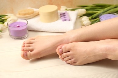 Photo of Woman with neat toenails after pedicure procedure on wooden floor, closeup