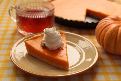 Piece of fresh homemade pumpkin pie served with whipped cream and tea on table