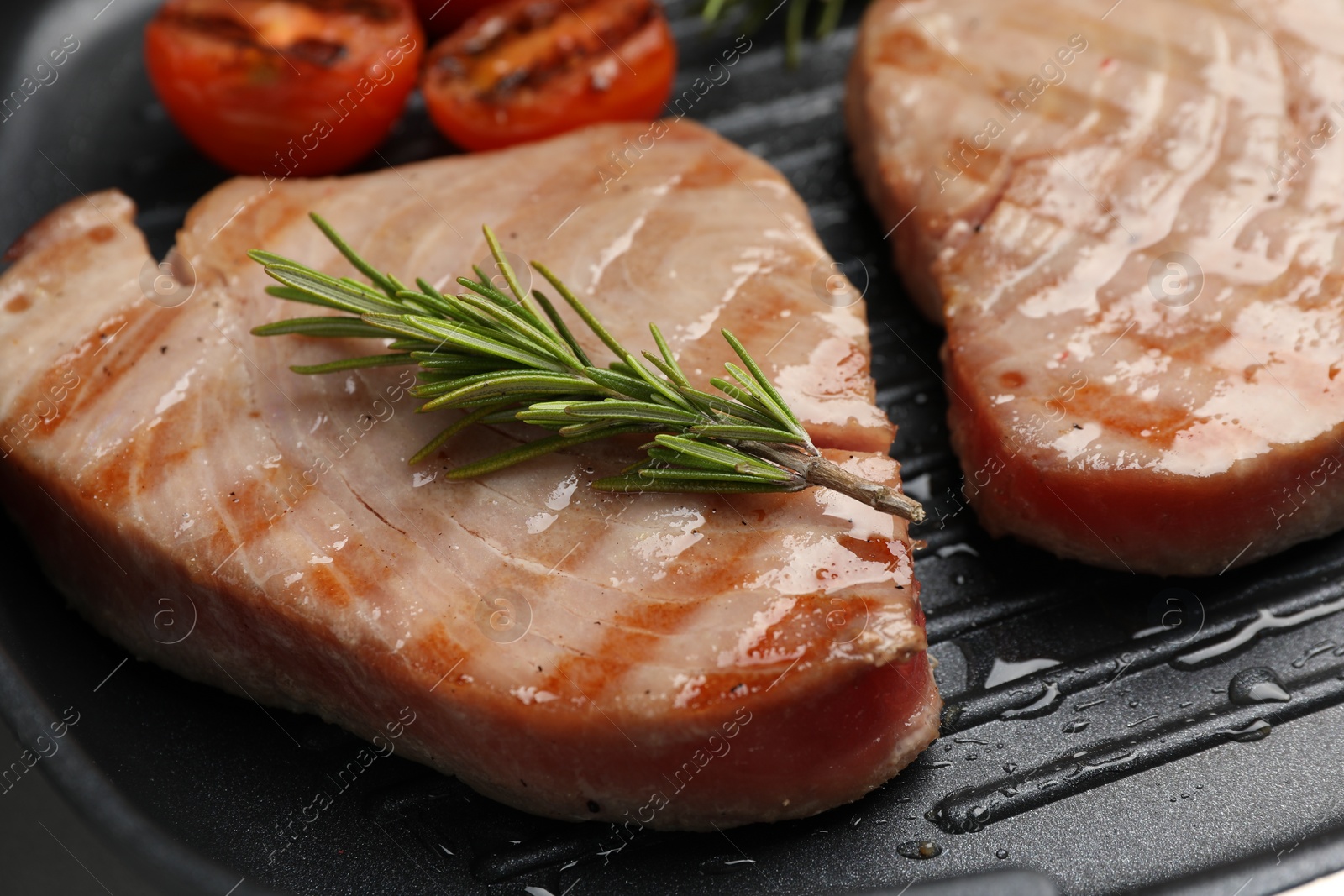 Photo of Delicious tuna steaks with rosemary in grill pan, closeup