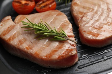 Photo of Delicious tuna steaks with rosemary in grill pan, closeup