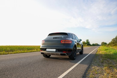 Modern black car on asphalt road outdoors