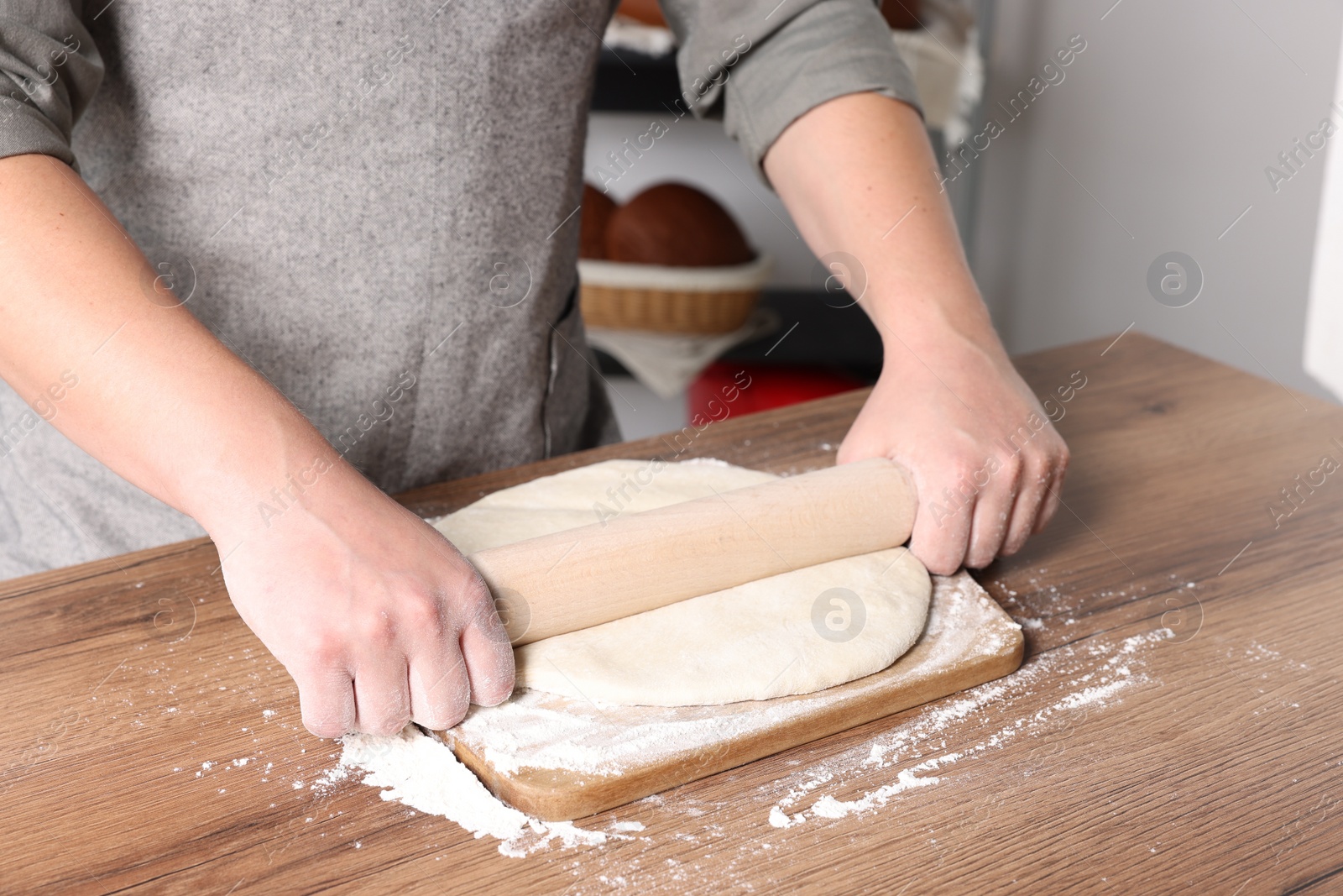 Photo of Man rolling dough at table in kitchen, closeup