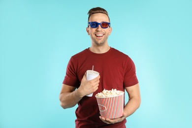 Photo of Man with 3D glasses, popcorn and beverage during cinema show on color background