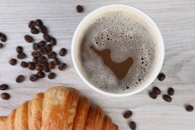 Photo of Coffee to go. Paper cup with tasty drink, croissant and beans on white wooden table, flat lay