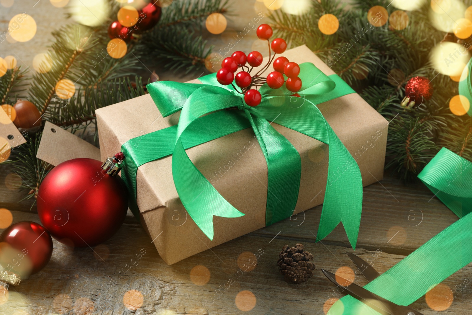 Photo of Christmas gift box with green bow and fir tree branches on wooden table