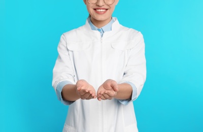 Photo of Female dentist holding something on color background
