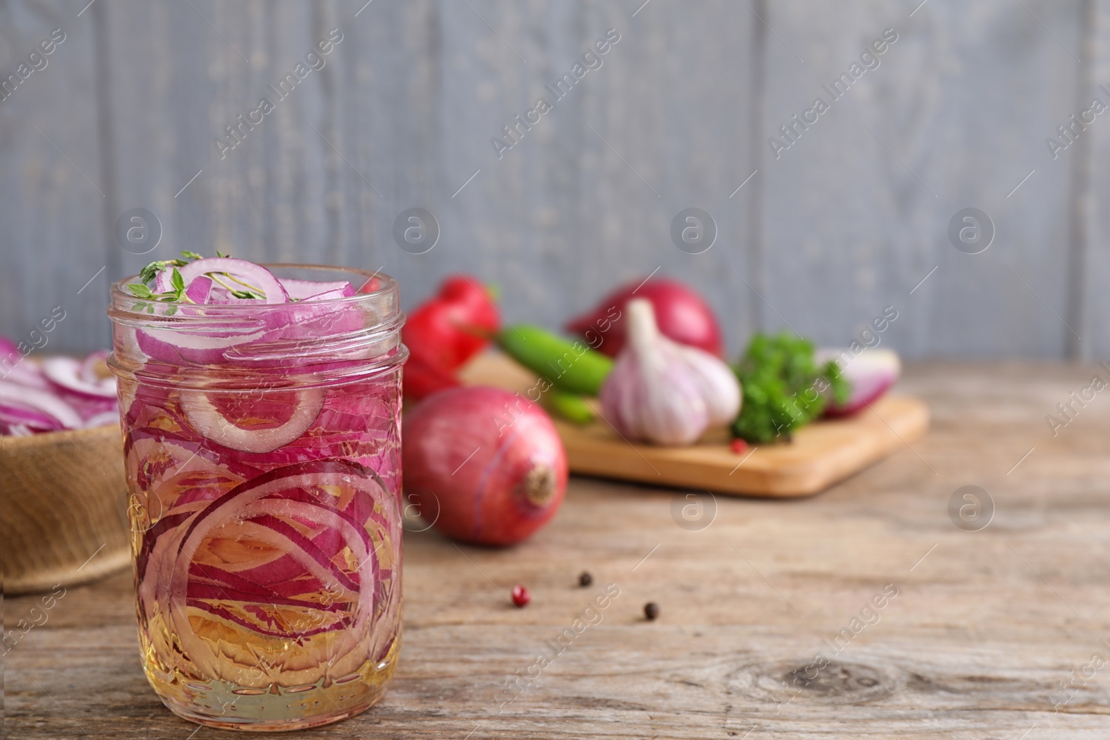 Photo of Jar of pickled onions on wooden table, space for text