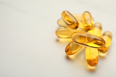 Dietary supplement capsules on white table, closeup. Space for text