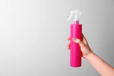 Photo of Woman holding spray bottle with hair thermal protection on white background, closeup. Space for text