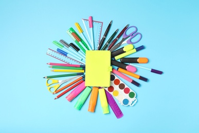 Photo of Different stationery and notebook on light blue background, top view. Back to school