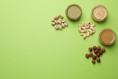 Photo of Different types of delicious nut butters and ingredients on light green background, flat lay. Space for text