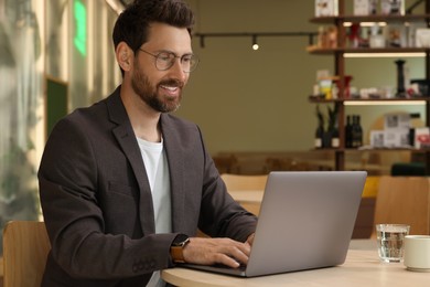 Photo of Man working on laptop at table in cafe