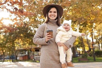 Happy mother with her baby daughter outdoors on autumn day