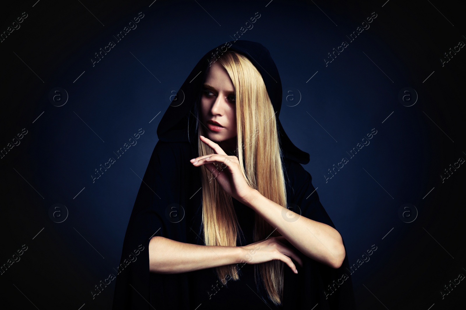 Photo of Witch in black mantle on dark background. Scary fantasy character