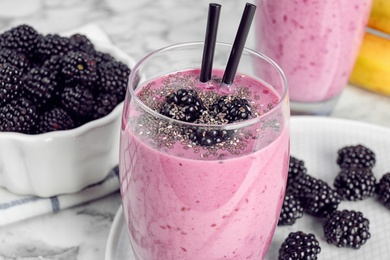 Photo of Delicious blackberry smoothie in glass on marble table, closeup