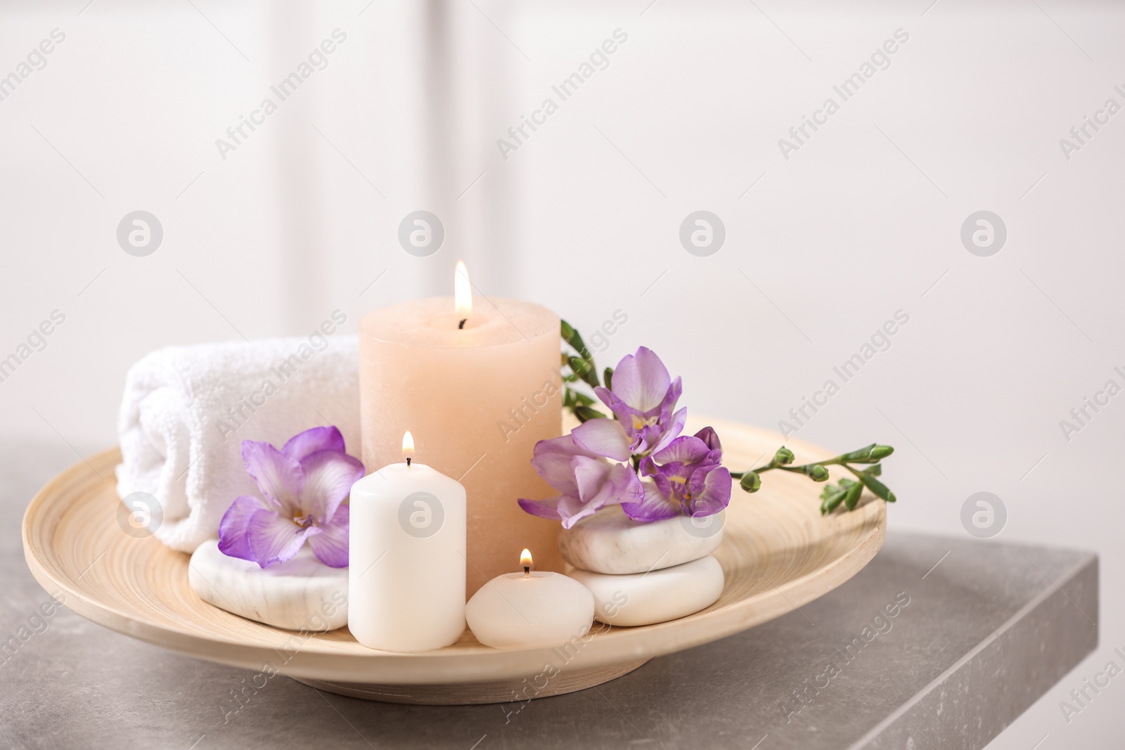 Photo of Beautiful composition with spa stones and burning candles on grey table