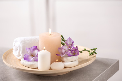 Photo of Beautiful composition with spa stones and burning candles on grey table