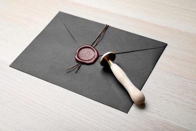Photo of Envelope with wax seal and stamp on white wooden table