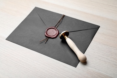 Envelope with wax seal and stamp on white wooden table