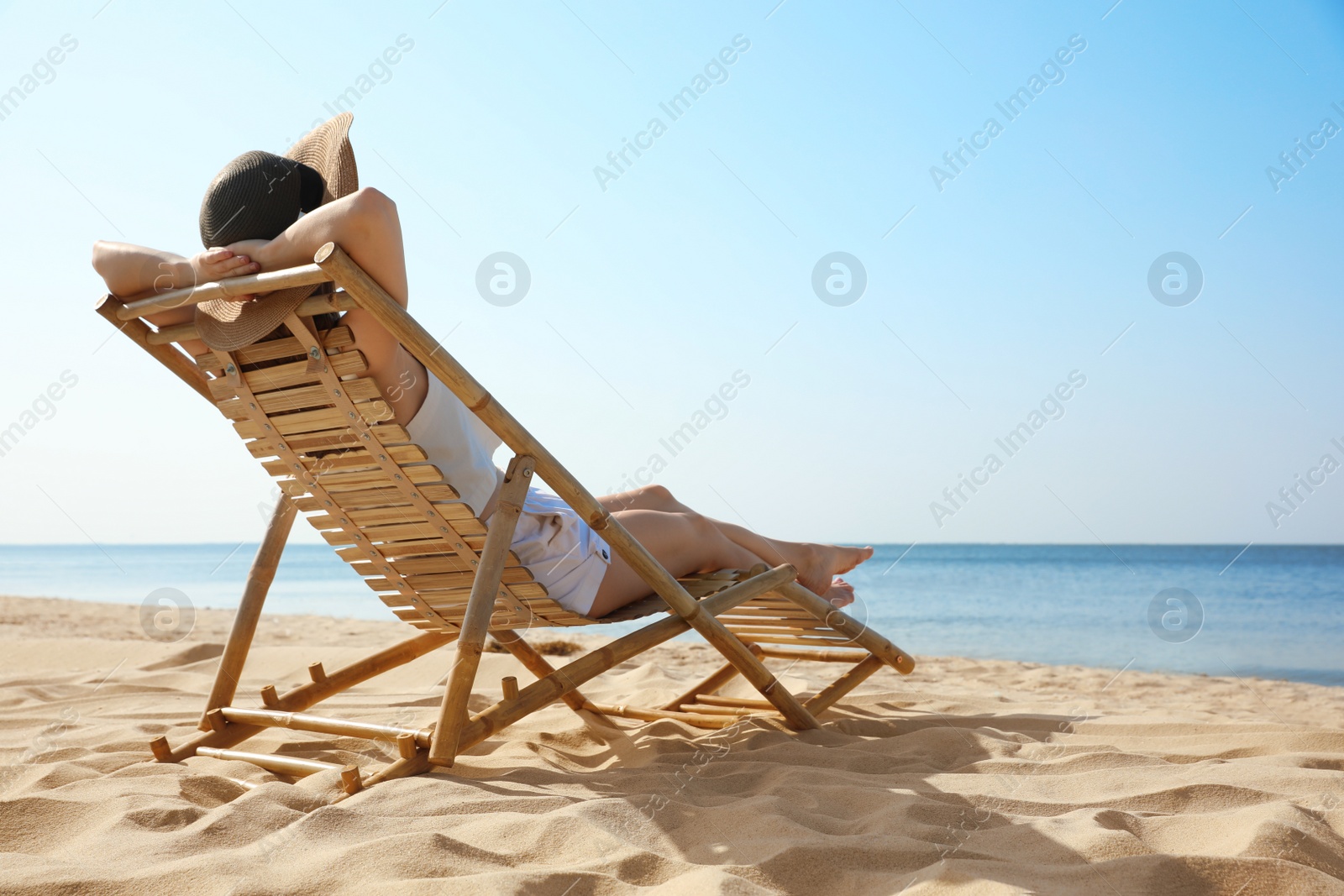 Photo of Young woman relaxing in deck chair on sandy beach