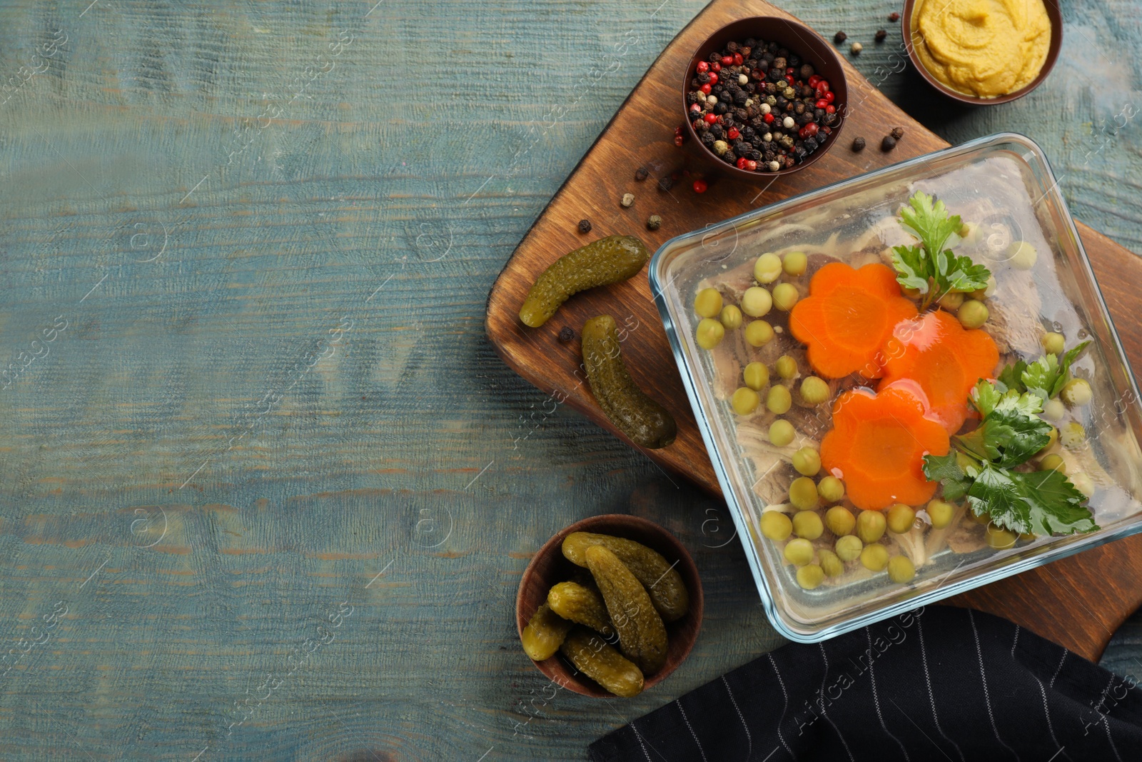 Photo of Delicious aspic and ingredients served on light blue wooden table, flat lay. Space for text