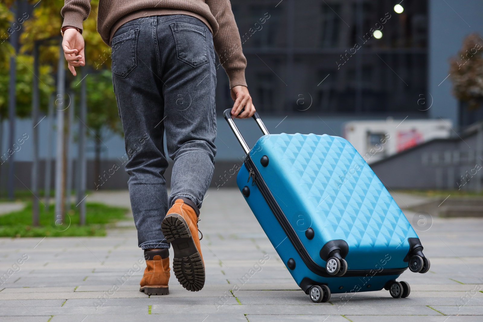 Photo of Being late. Man with light blue suitcase walking outdoors, closeup