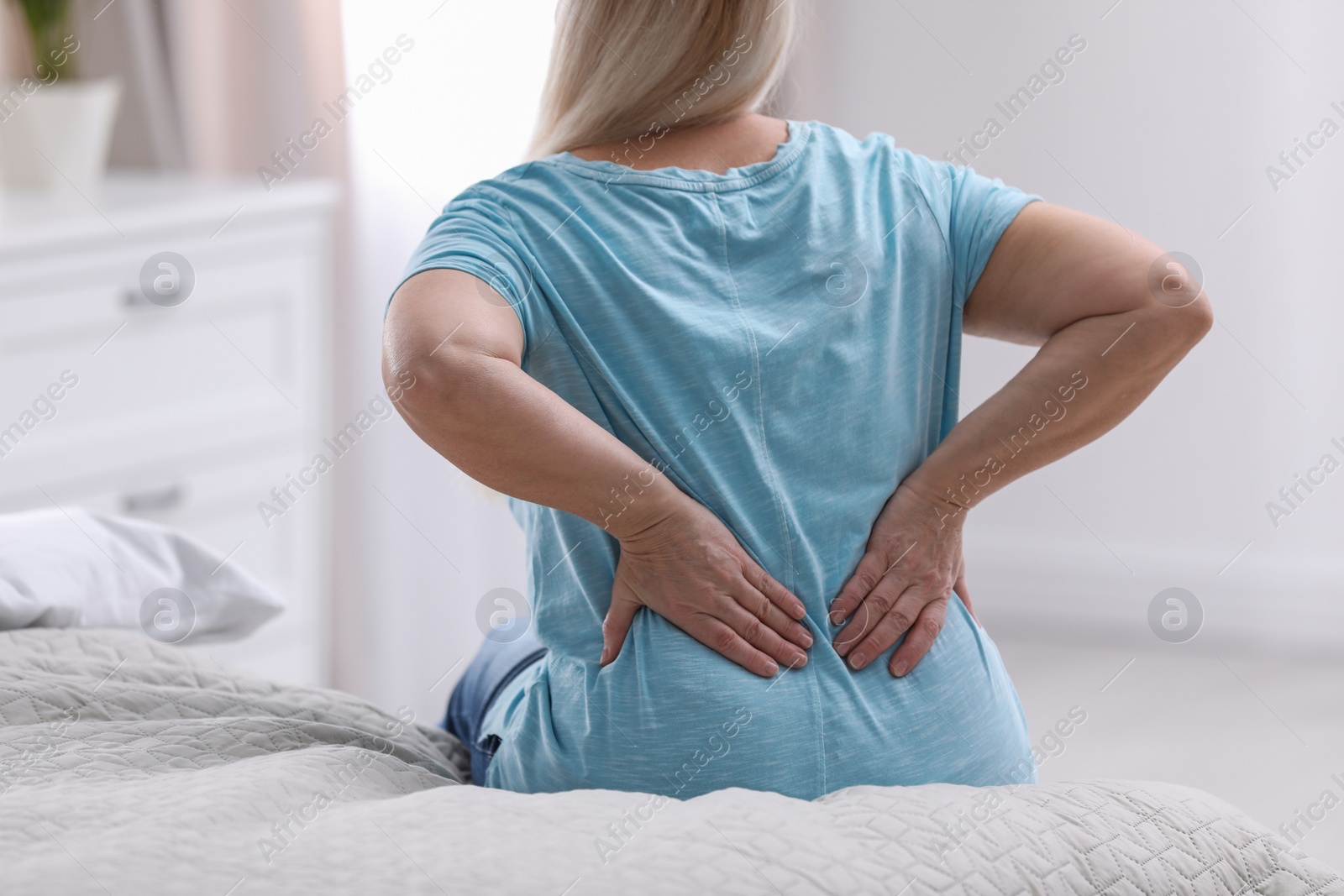 Photo of Senior woman suffering from back pain at home, closeup